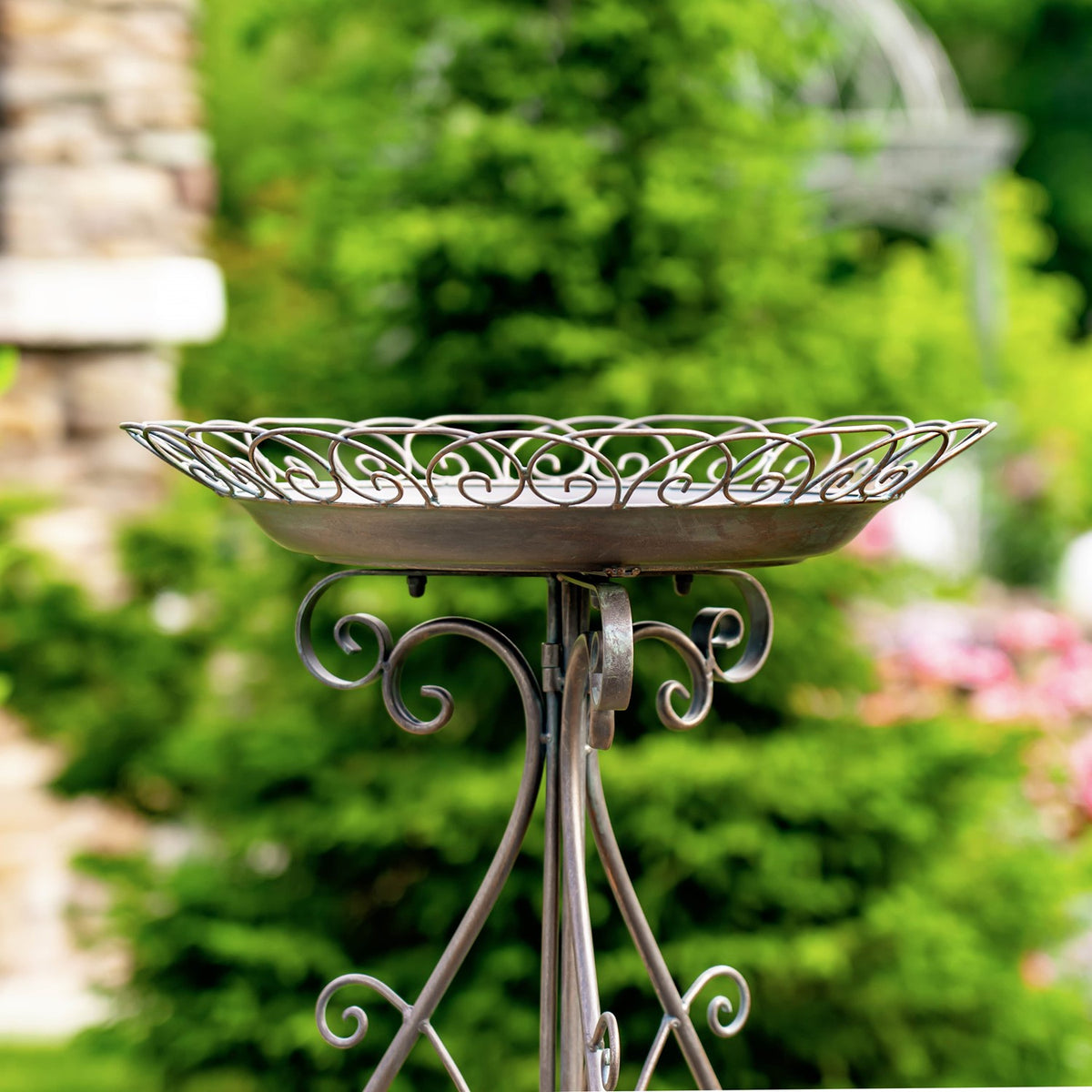Side profile highlighting the birdbath's raised scrollwork rim and curled supports