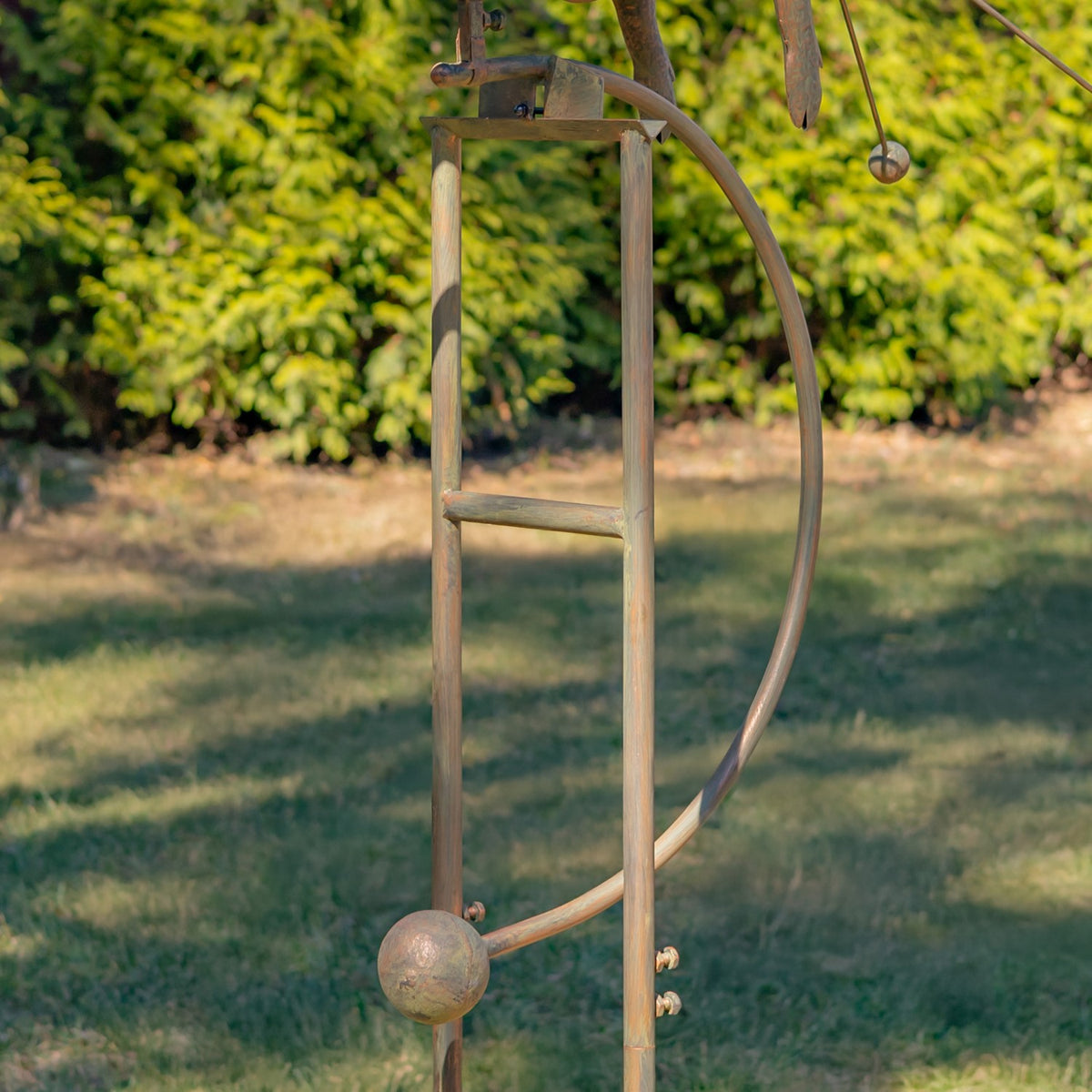Lower iron stake detail showing a curved rod, crossbar, and round metal weights.