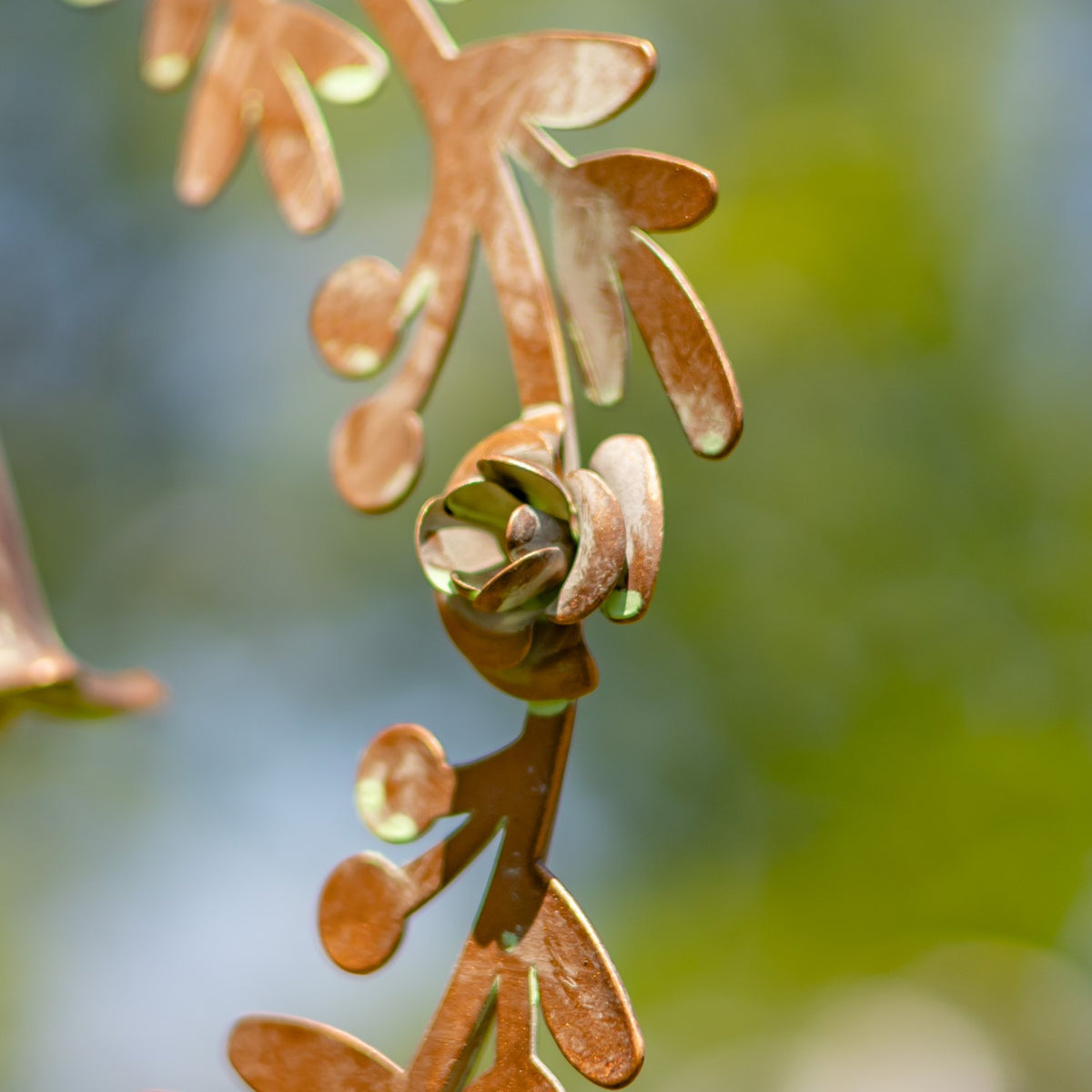 A small metal bell is nestled among copper-toned leaves in a close-up of the wreath.