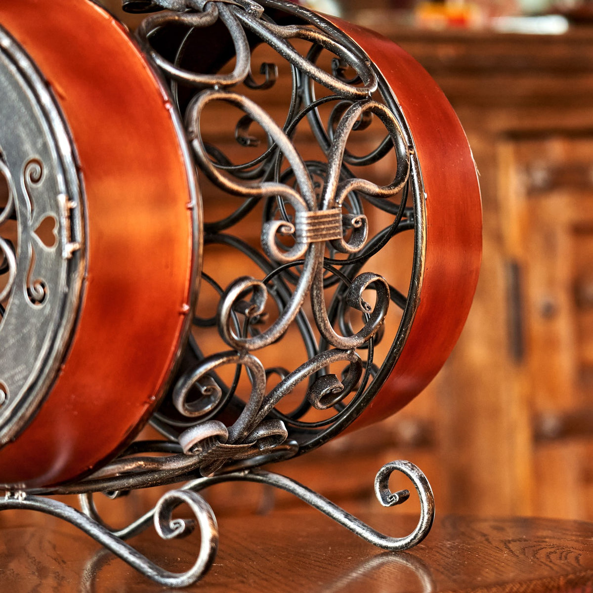 Close-up of curled metal scrollwork between the reddish-brown bands, with part of the curved foot visible.