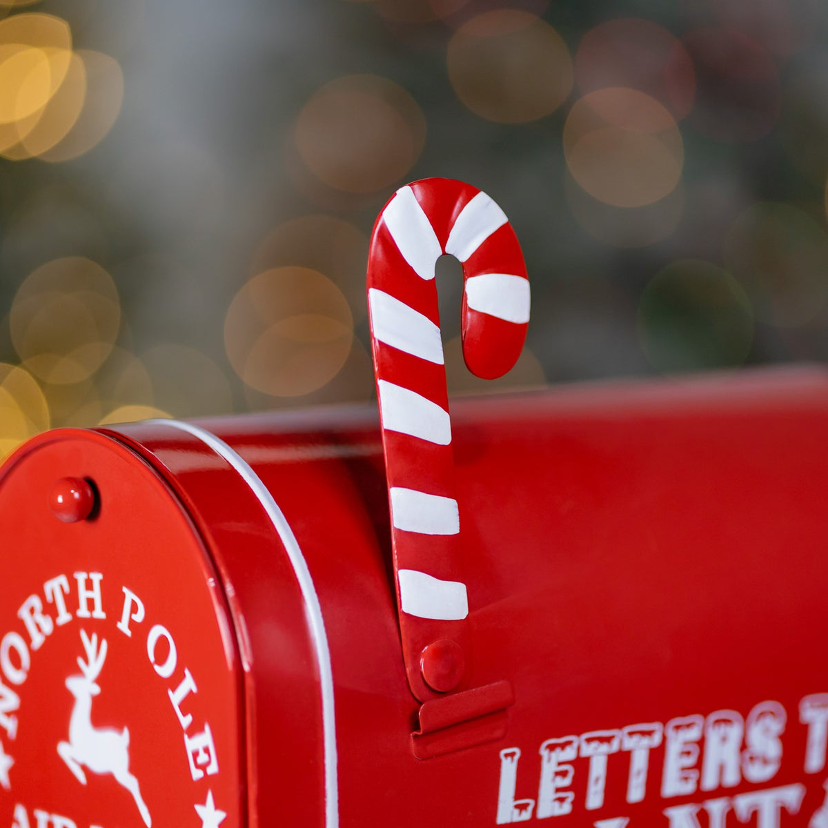 Close-up of a red mailbox with a red-and-white striped candy cane hook.