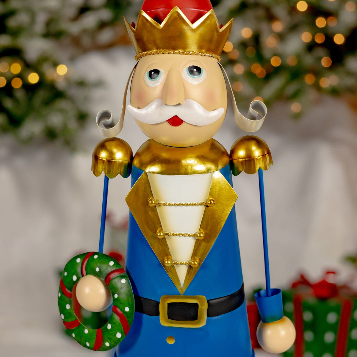 A blue-coated nutcracker holds a candy cane wreath beside its gold-trimmed uniform.
