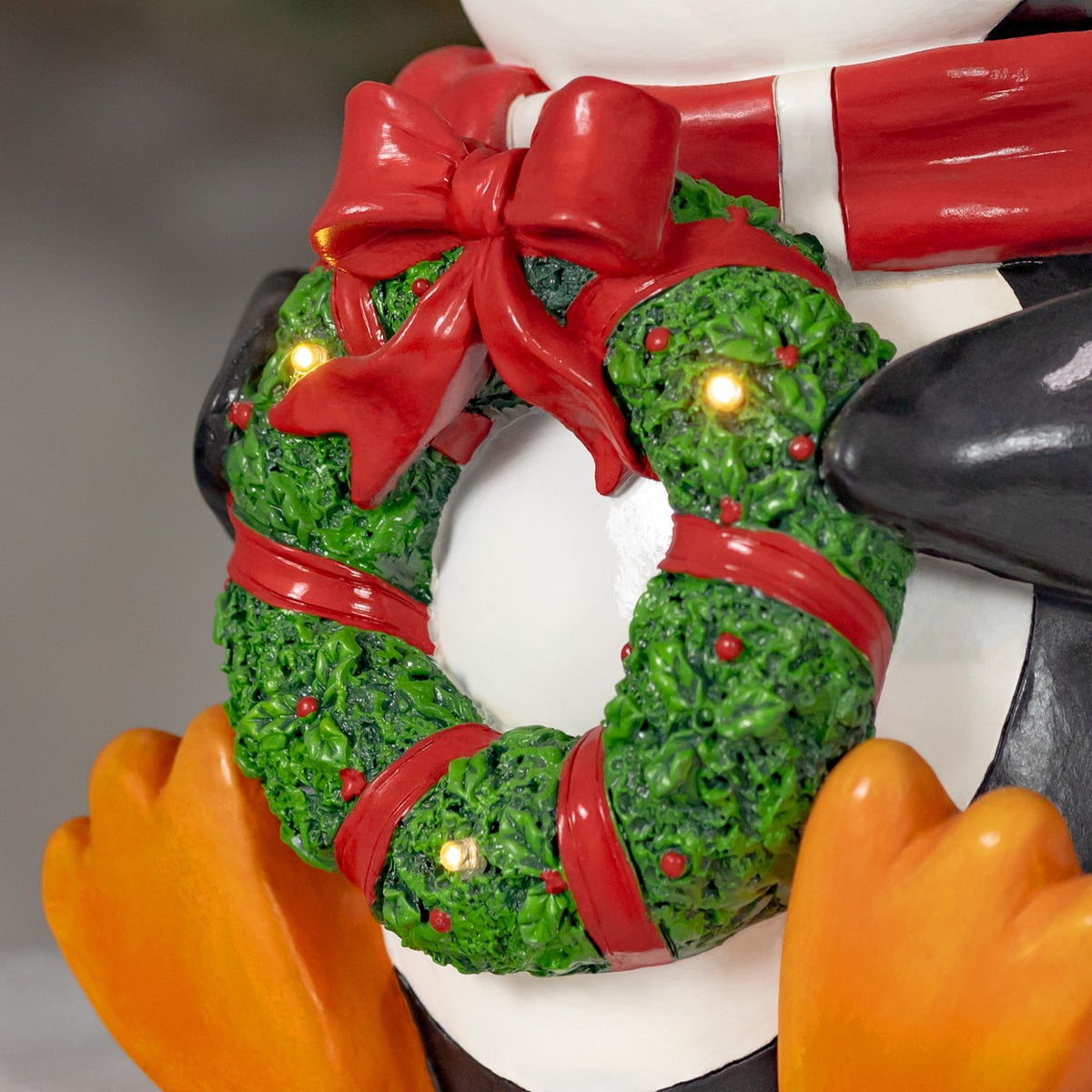 Close-up of the textured green wreath with red bows, berries, and glowing lights.