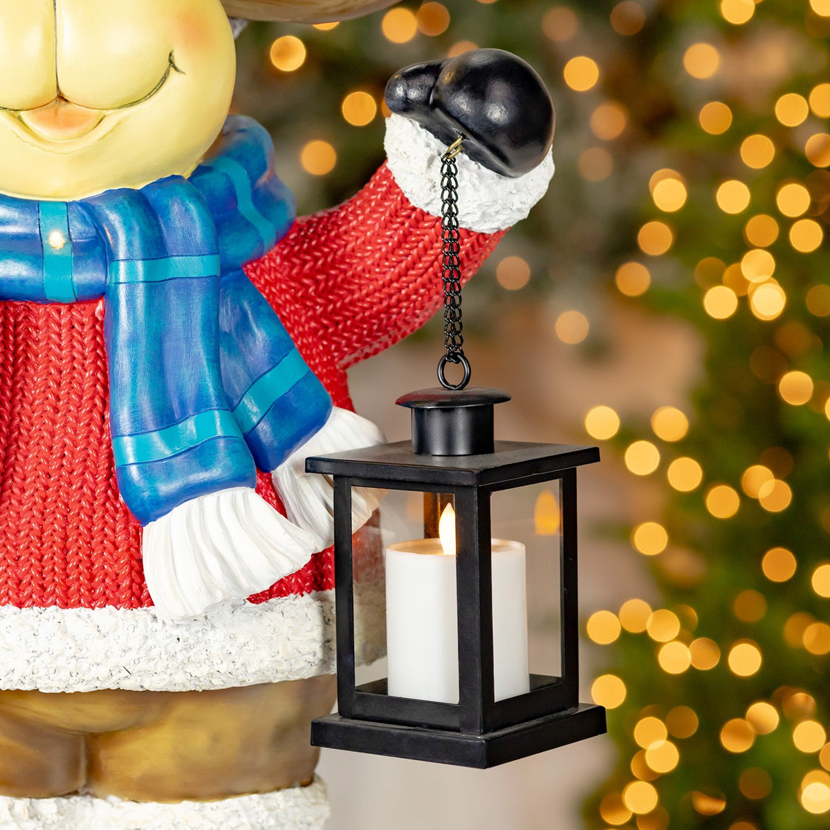 Close-up of the black hanging lantern with a lit candle beside the moose’s scarf and sleeve.