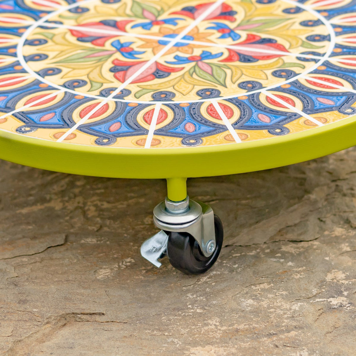 Close-up of the trolley’s green rim, mosaic surface, and metal caster wheel.