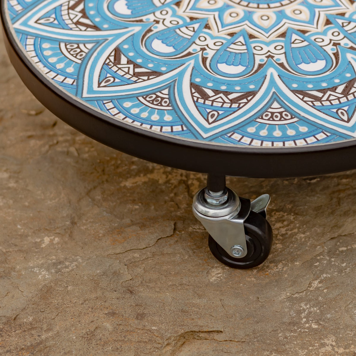 Close-up of a caster wheel and dark rim beneath the trolley's patterned top.