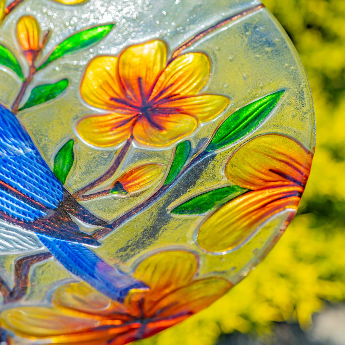 Close-up of raised orange flowers and green leaves beside part of the bluebird design.