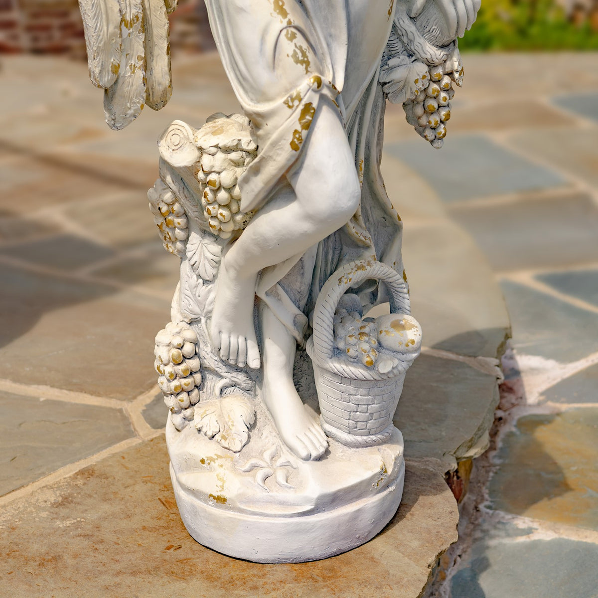 Close-up of the statue’s draped skirt, crossed legs, grape clusters and small basket on the base.