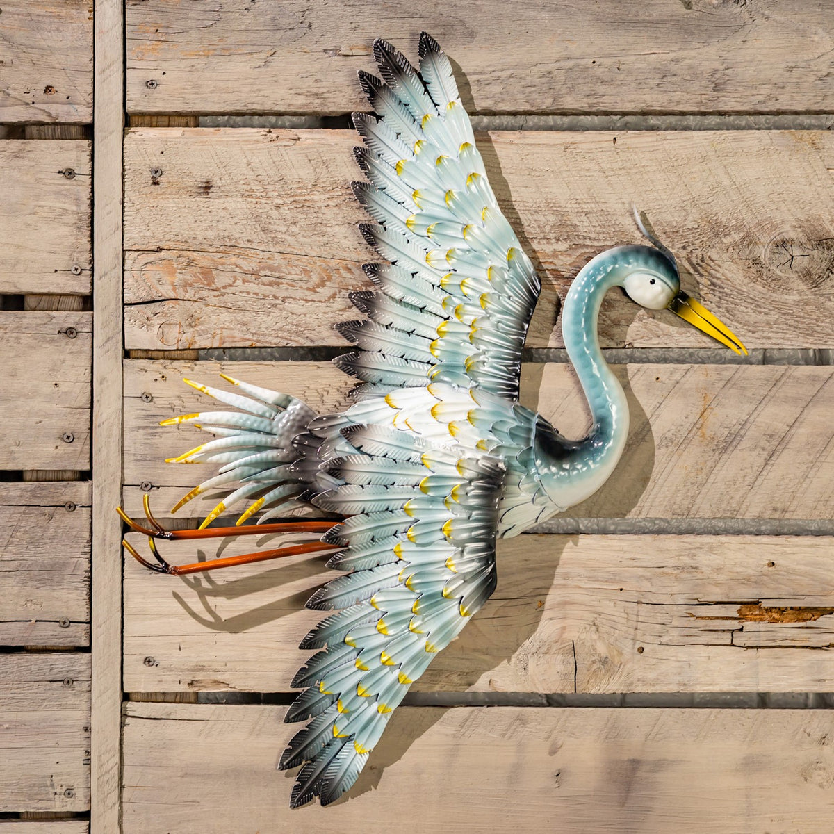 A crane wall decoration in flight, with outstretched wings and legs extending behind it.