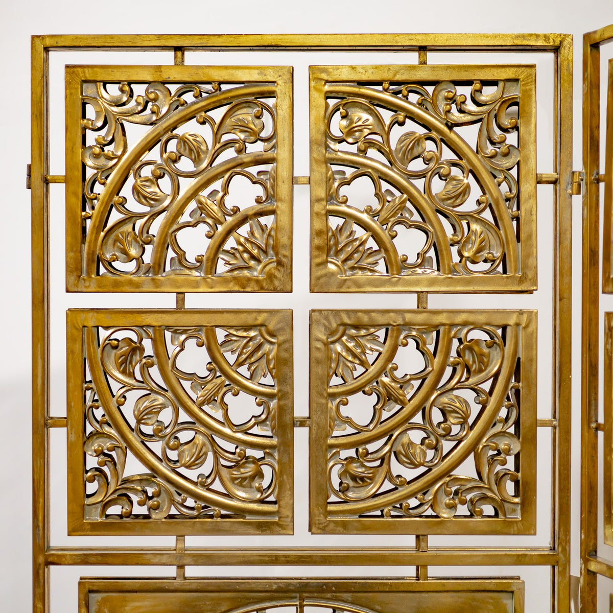Close-up of gold scrollwork in four square openings within the screen’s rectangular frame.