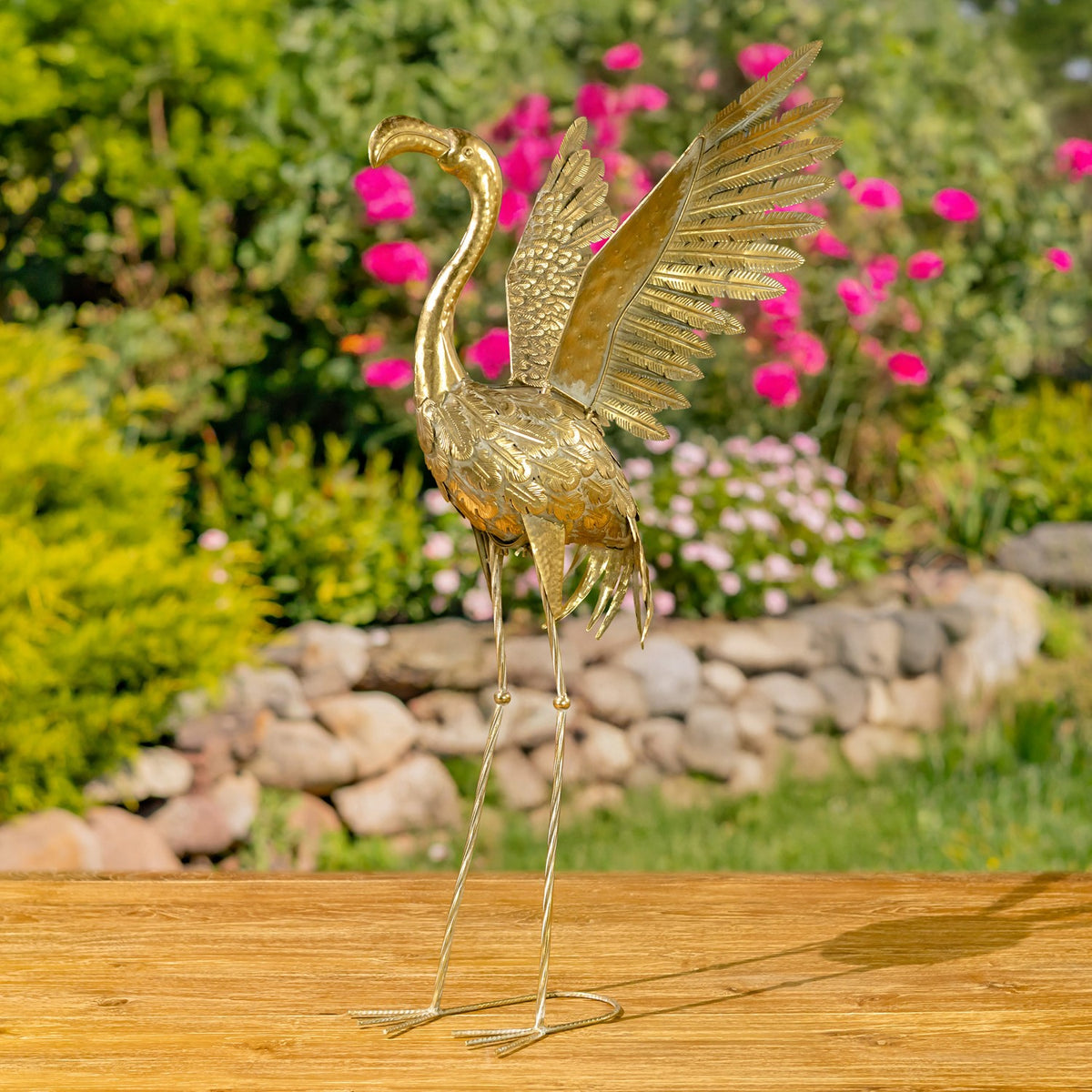 A gold flamingo figurine viewed from behind, with one large feathered wing raised above its body.