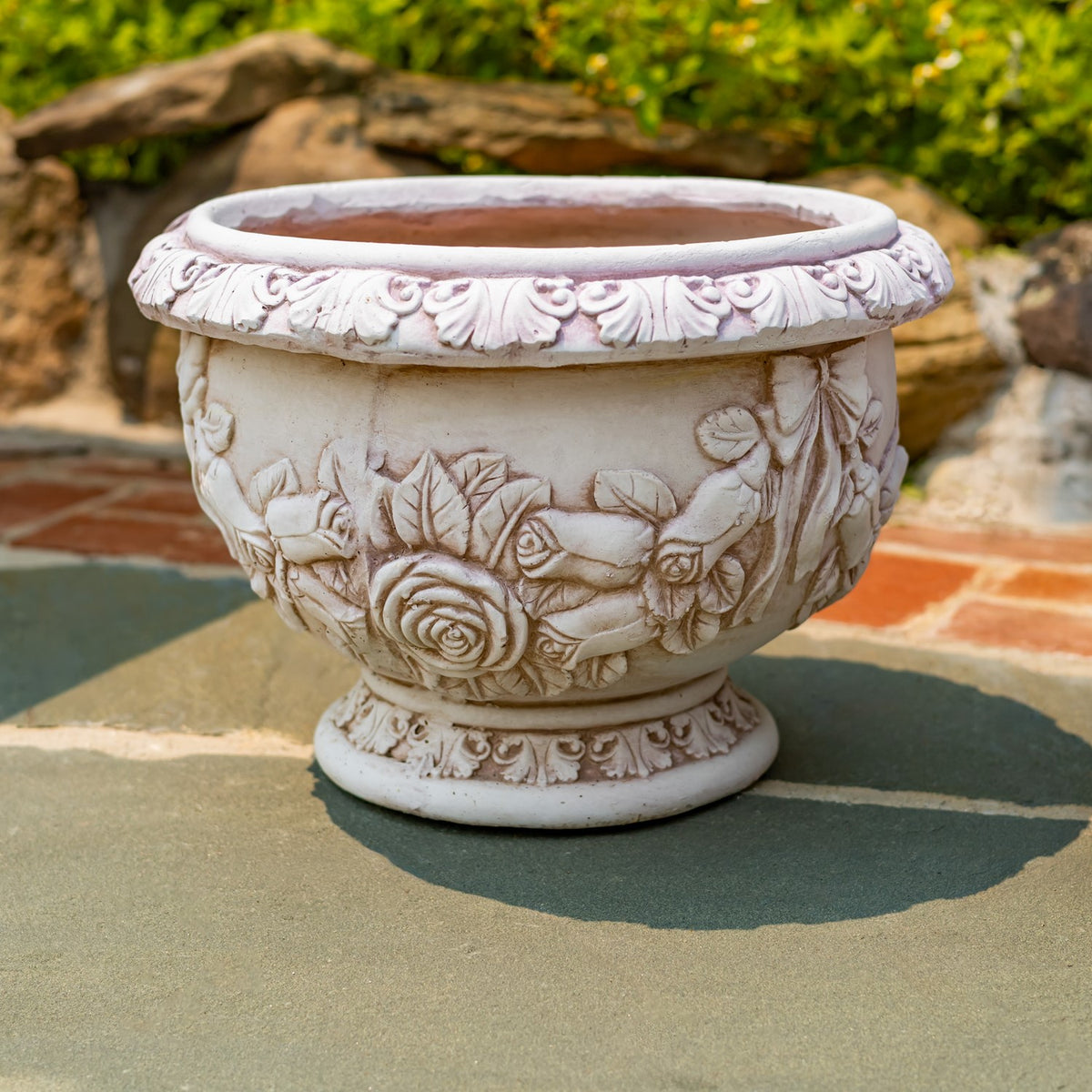 A single pale floral-relief urn planter with its empty interior visible from above.