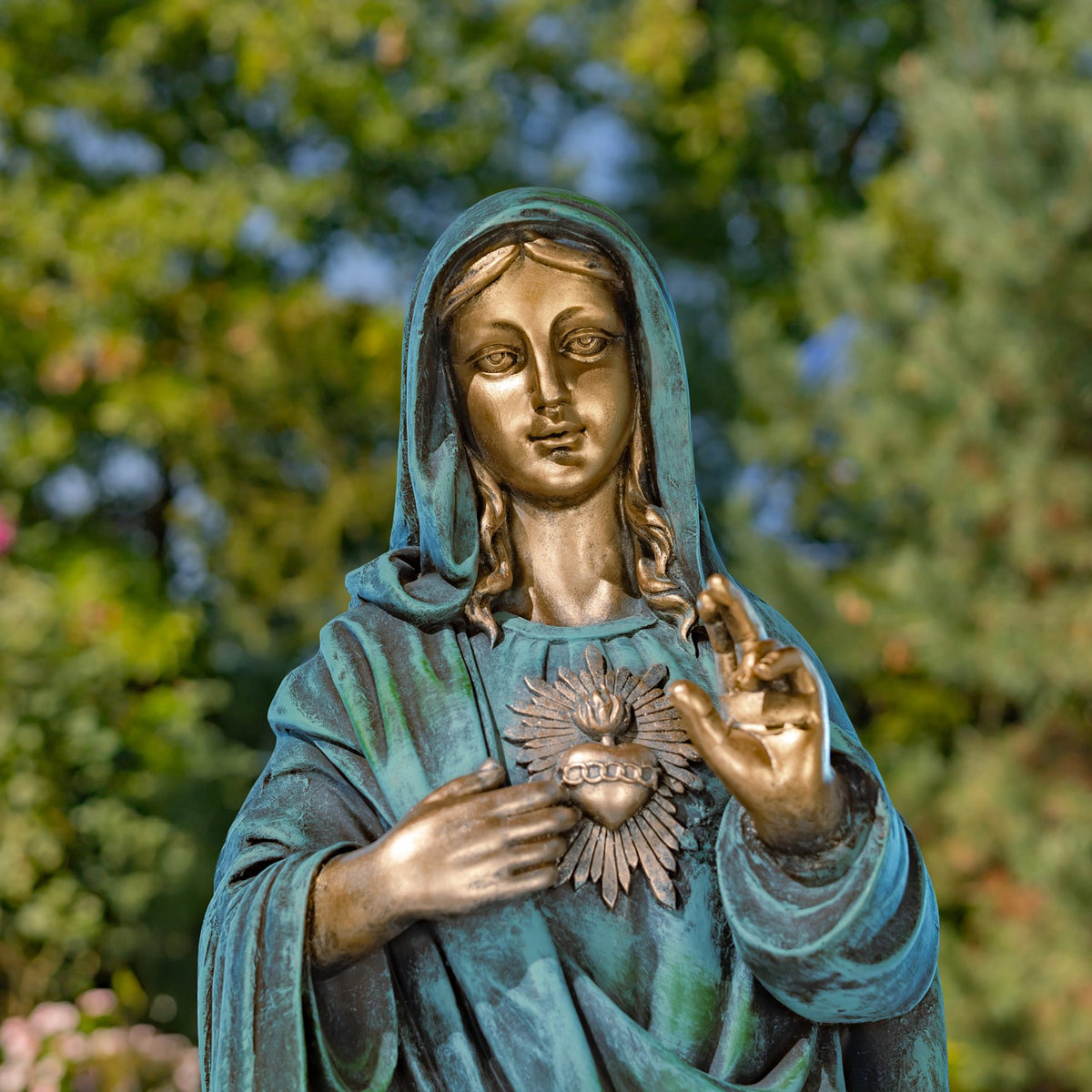 Front view of Mary's serene face and hands framing the radiant heart on her robe.