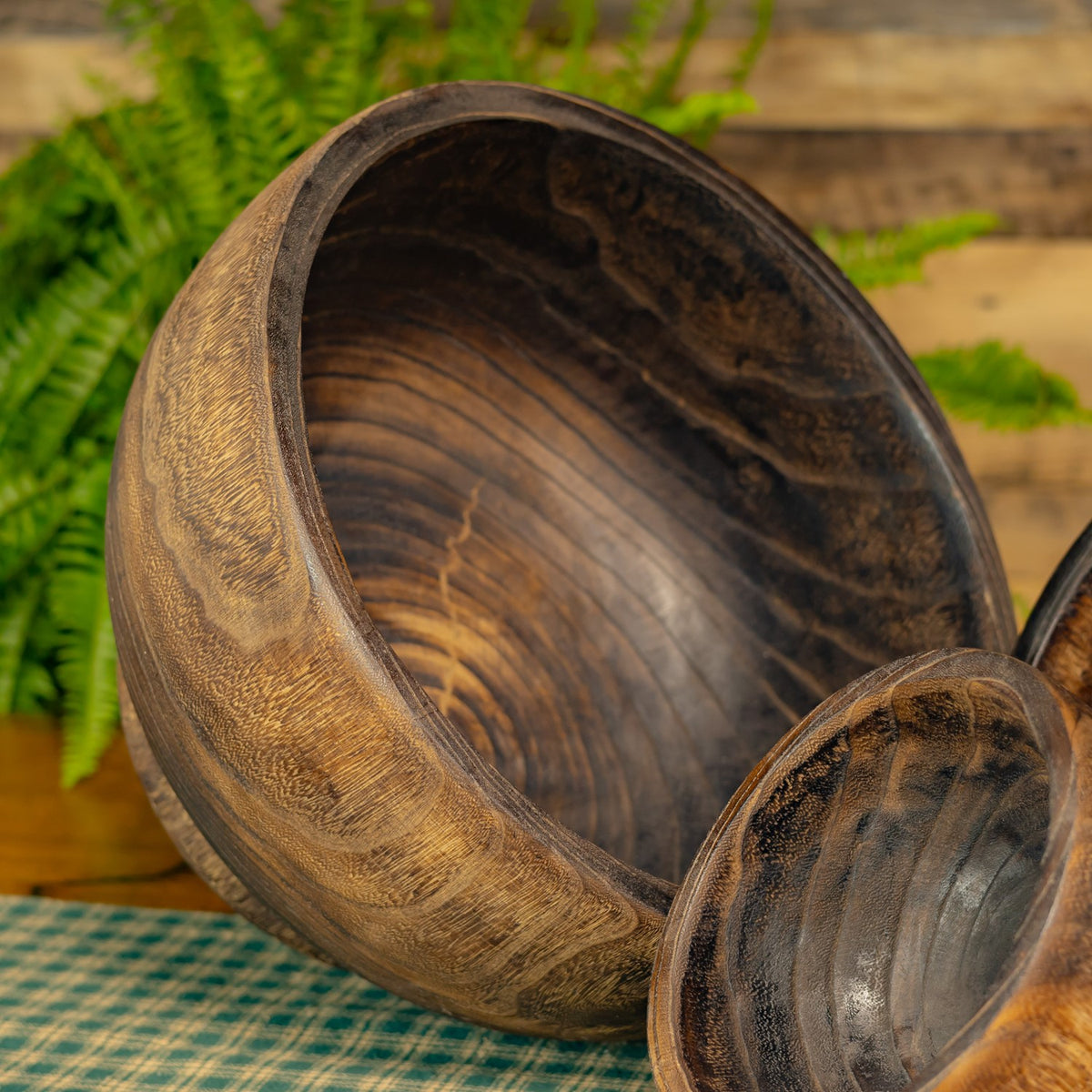 Close-up of a large wooden bowl tilted to reveal its dark, visibly grained interior.