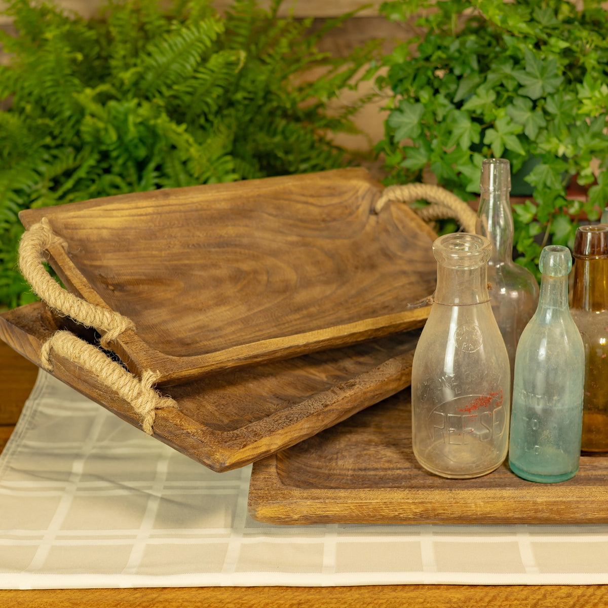 Close view of a brown wooden tray with rope handles on a table