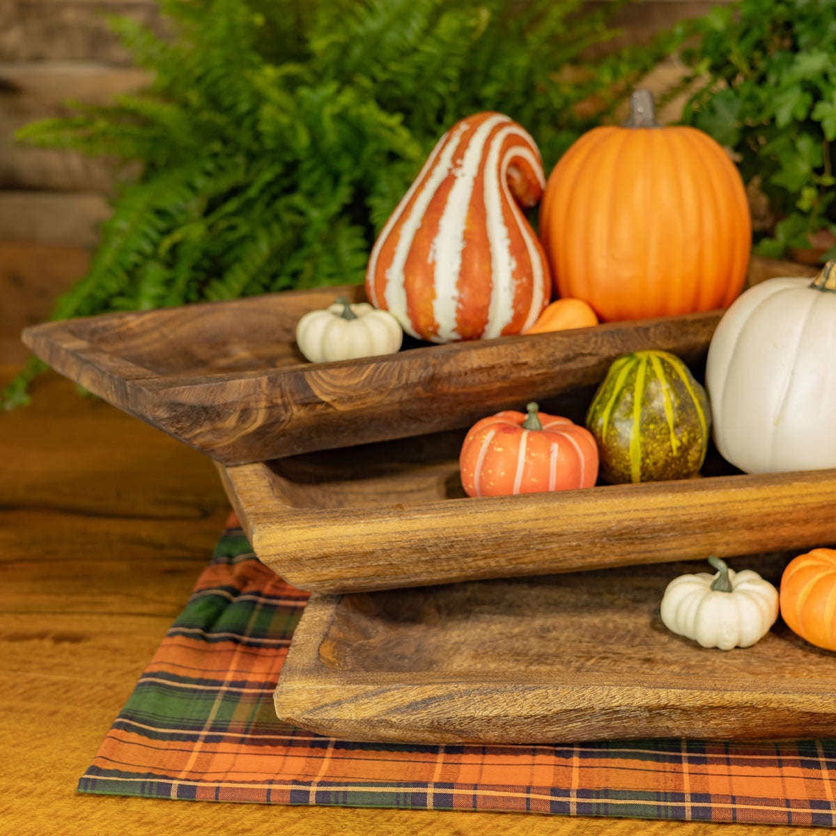Close view of overlapping rustic wooden tray edges beneath small pumpkins and gourds.