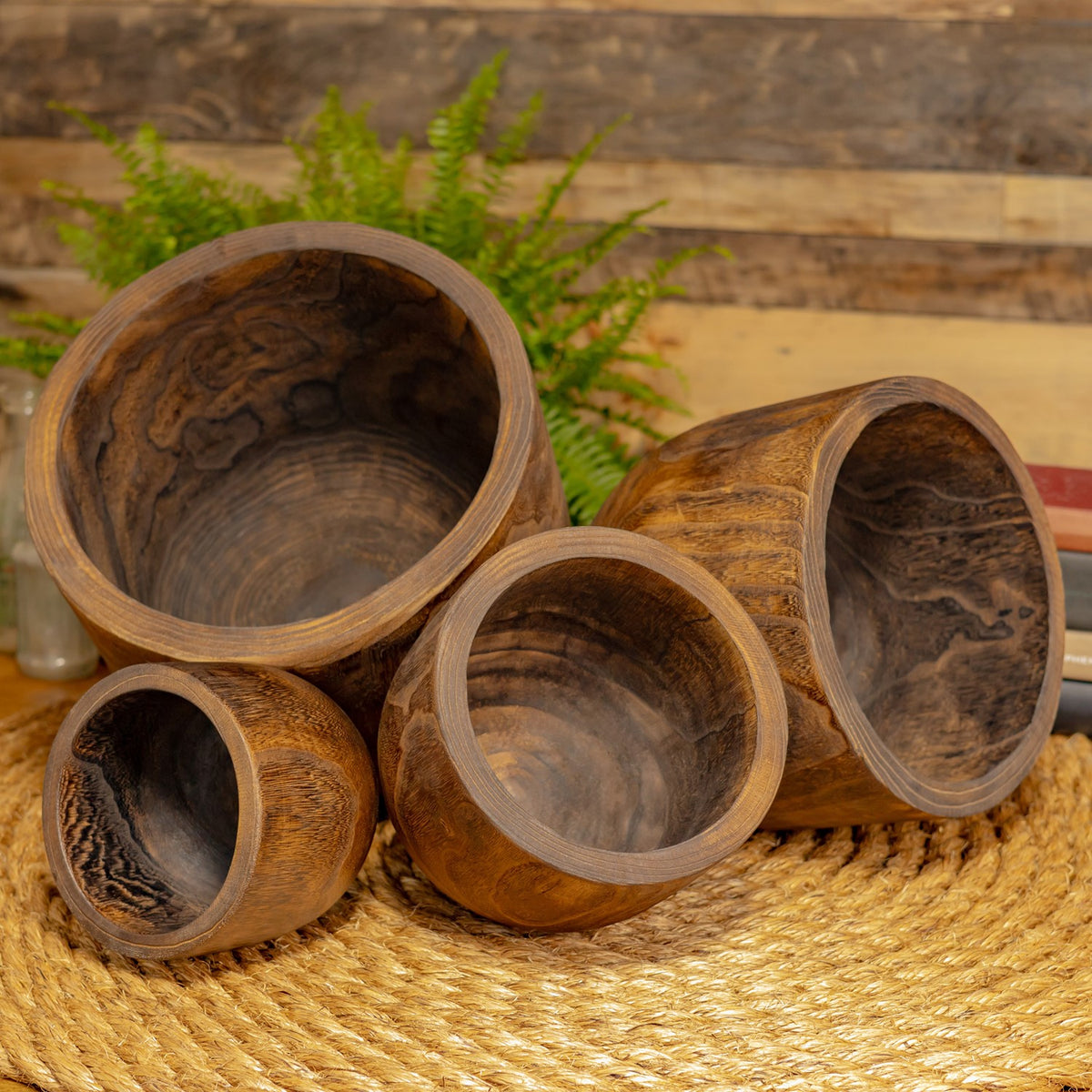 Four wooden bowls tilted toward the camera to show their interiors and natural grain.
