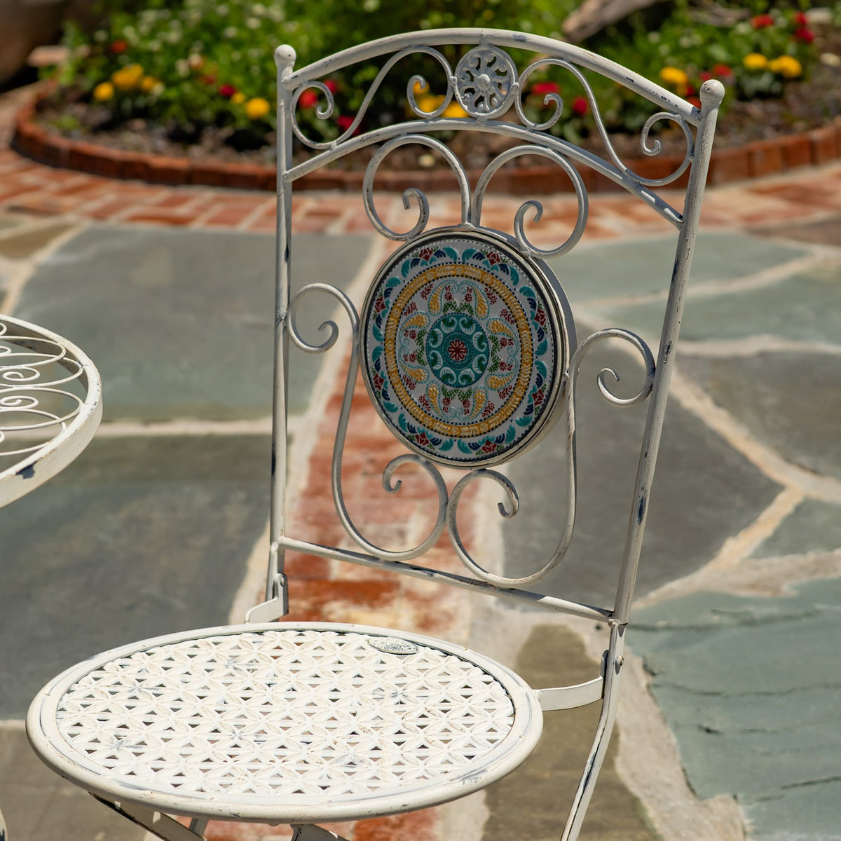 Ornate white metal chair with a circular mosaic back medallion and woven-pattern seat.