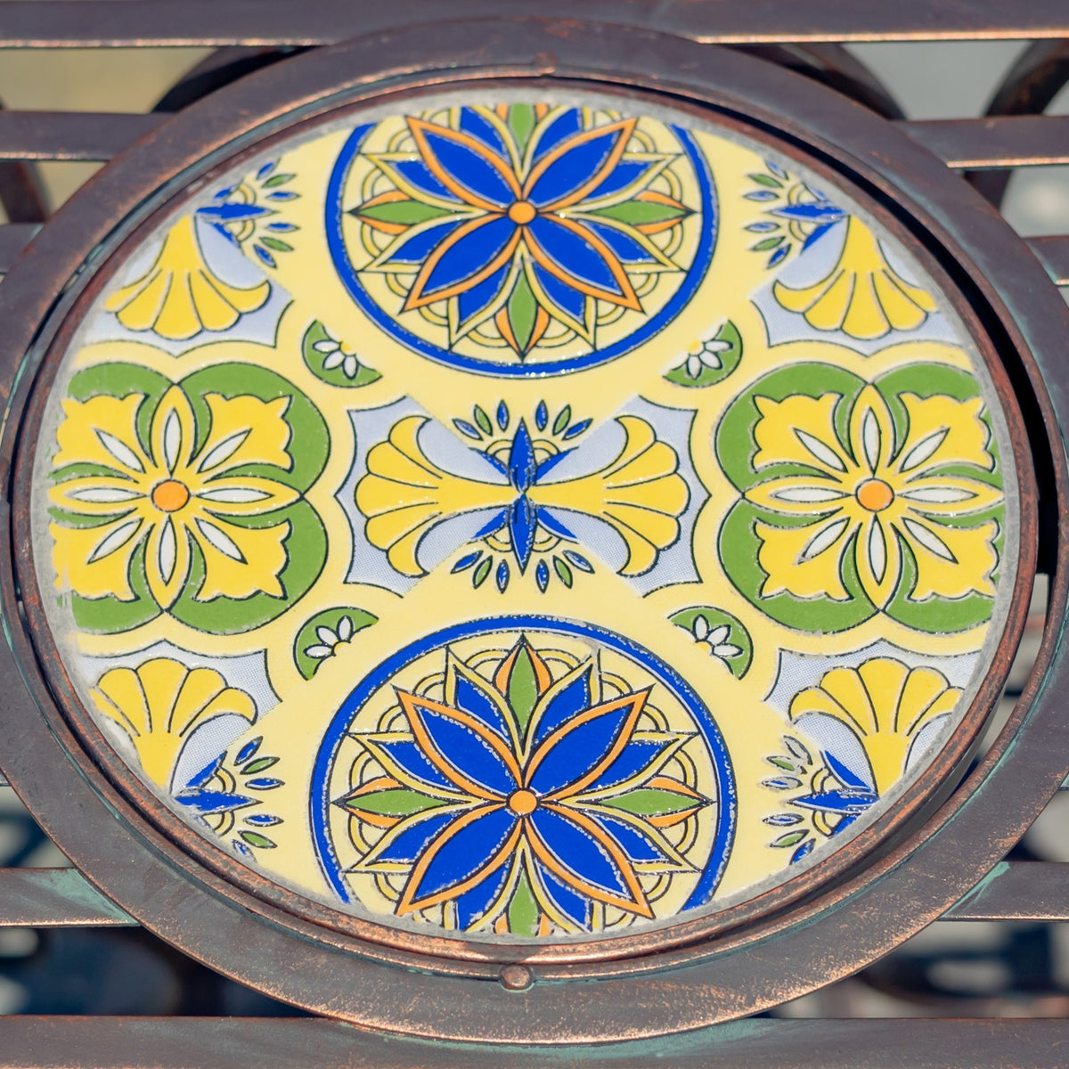 Close-up of the stand’s round tile top, with blue, yellow, and green floral motifs inside a dark metal rim.