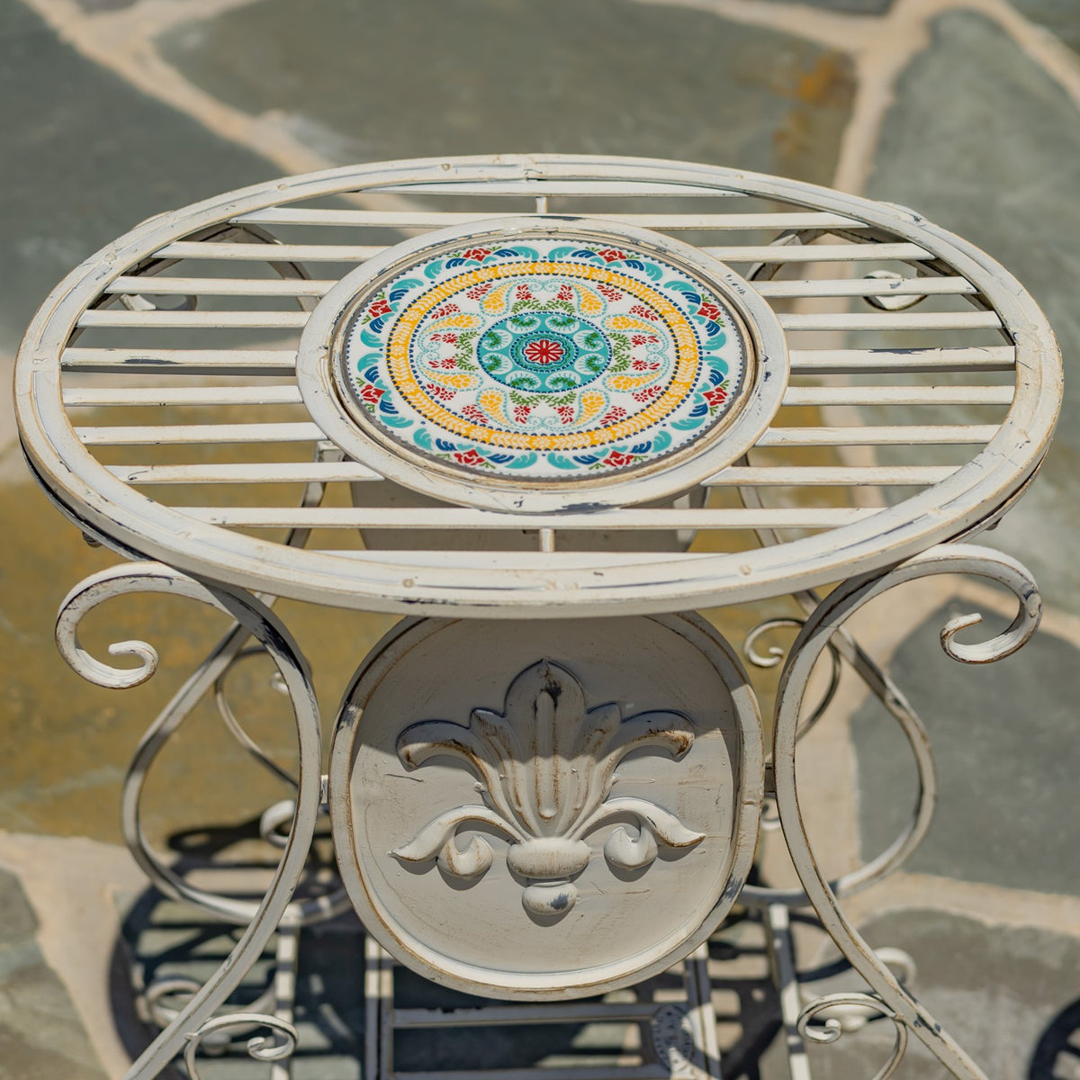 Close-up of the stand’s round tabletop, with a colorful patterned mosaic surrounded by pale metal slats.
