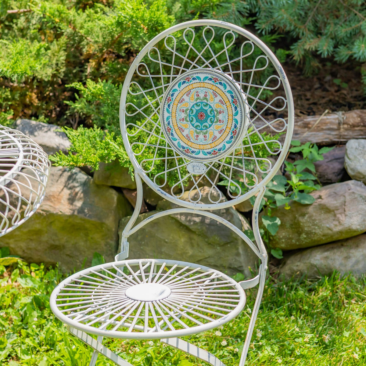 Close-up of a round-backed wire chair with a colorful circular mosaic inset and radial wire seat.