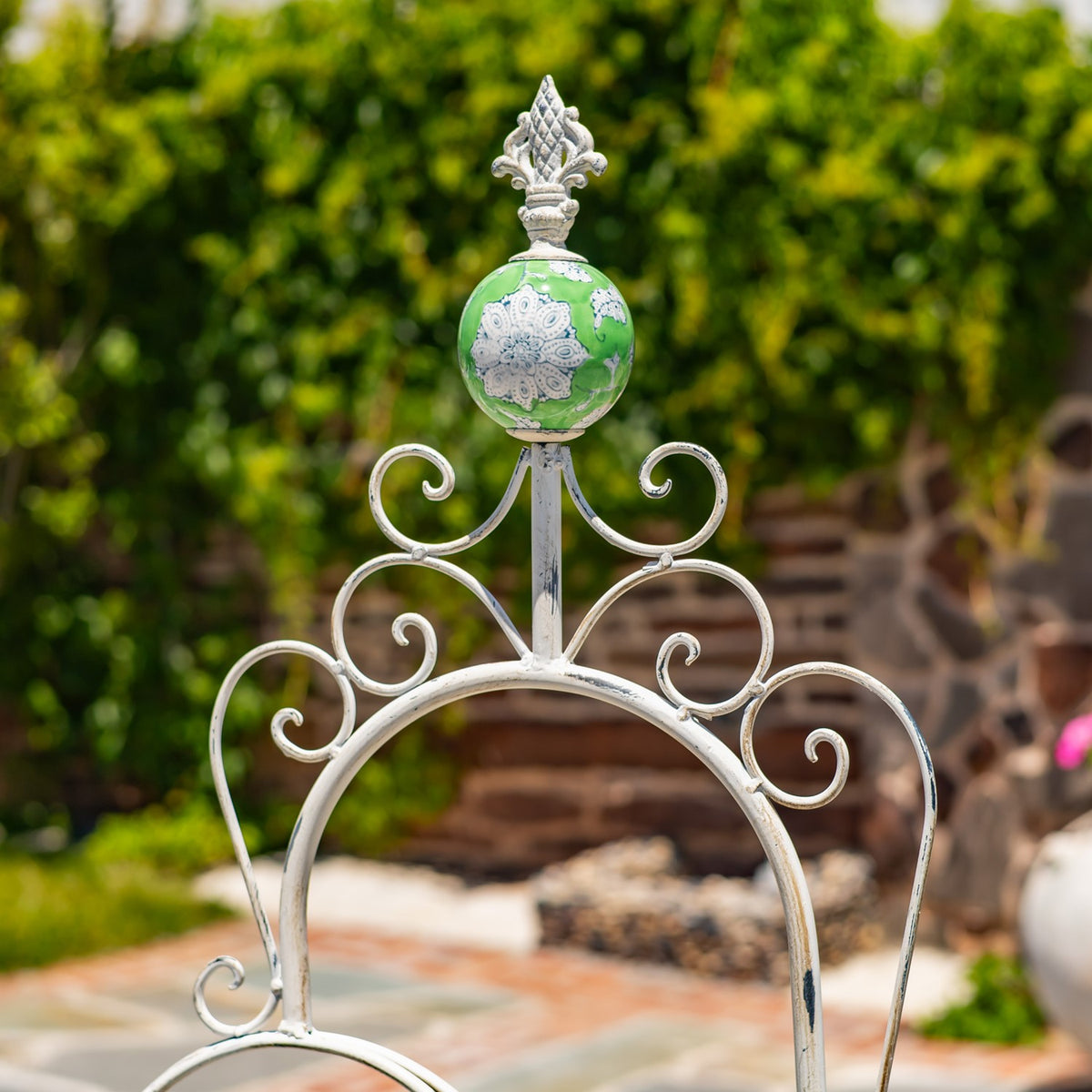 Close-up of the stand’s curled metal ornament and green-and-white finial.