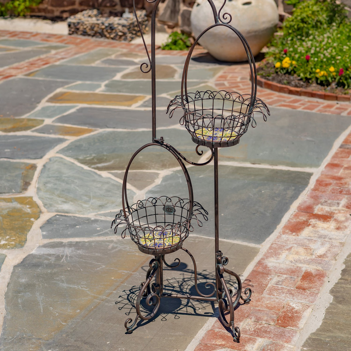 Close view of the empty wire baskets and ornate curled base of the metal plant stand.