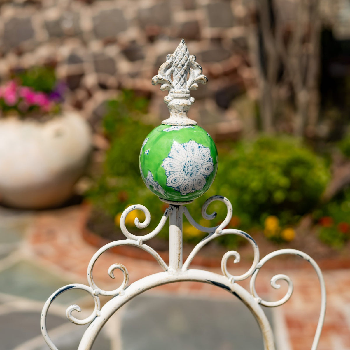 Close-up of a green decorative ball and pointed finial above the stand’s white scrollwork.