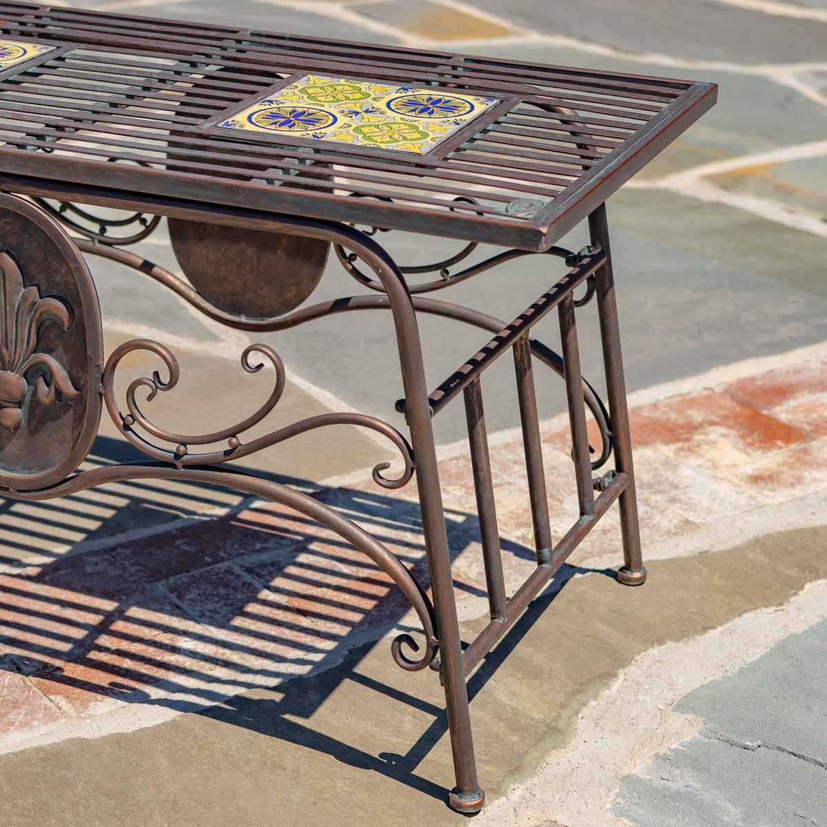 Angled view of the table's slatted top, curved metal supports and decorative scrollwork.