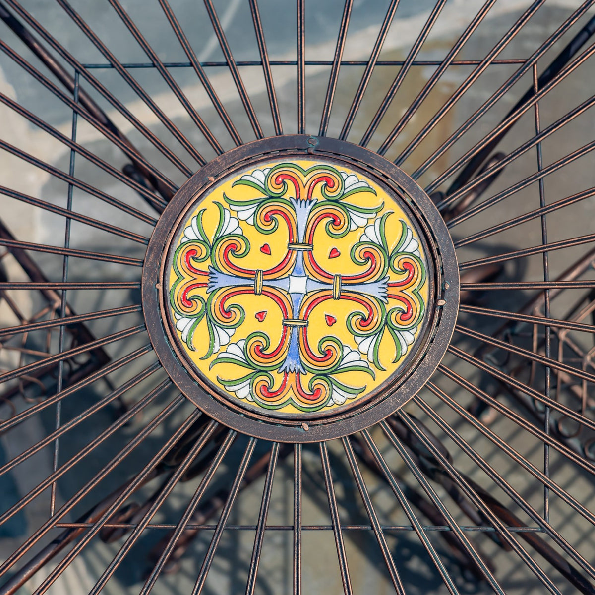 Close-up of a yellow floral-patterned mosaic medallion surrounded by radiating metal table supports.