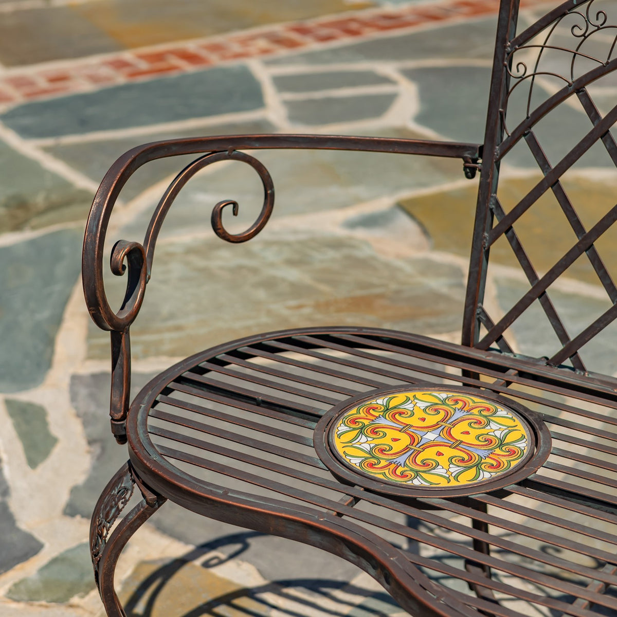 Close-up of a curled metal arm beside the slatted seat and a colorful circular mosaic inset.