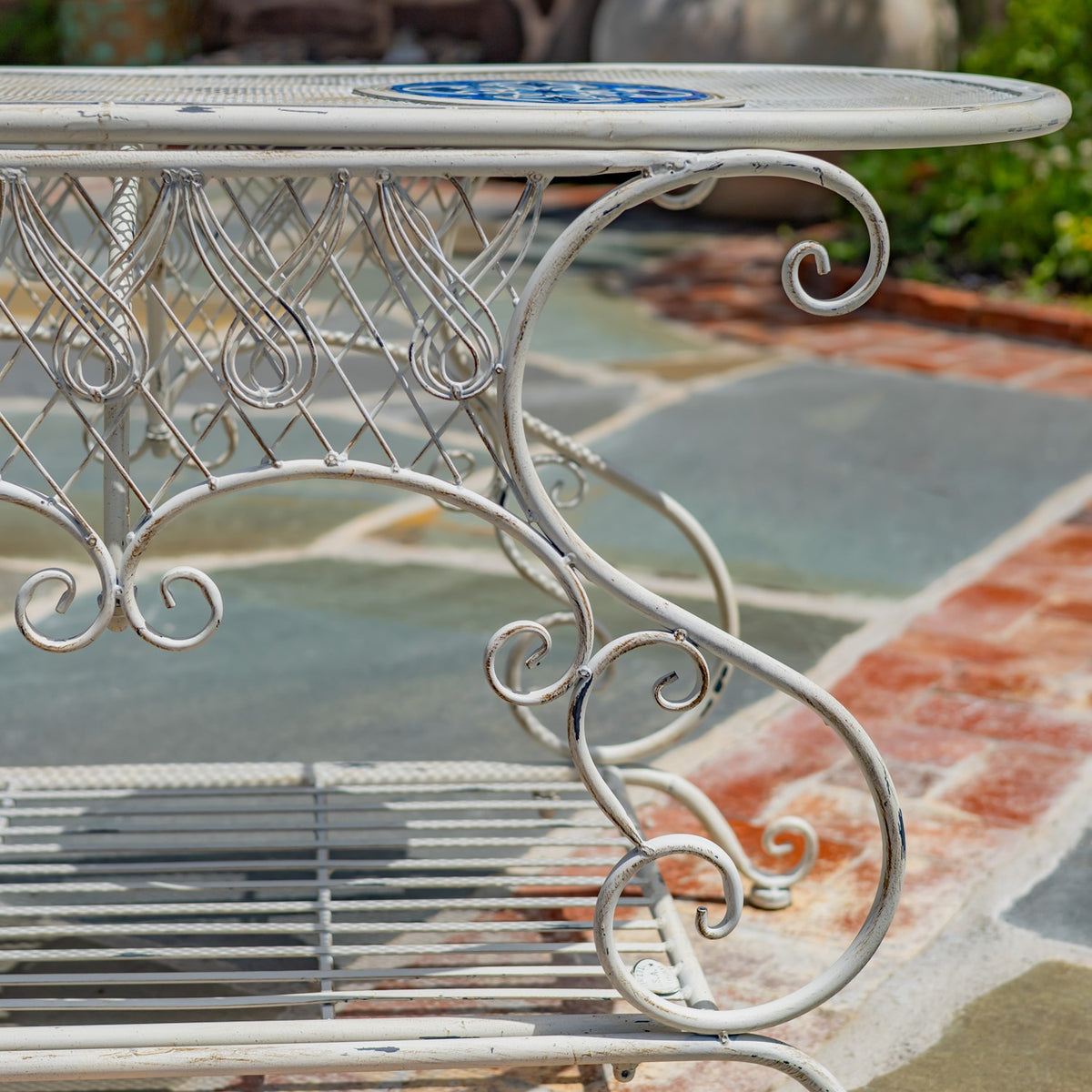 Close-up of the table’s curled metal leg and decorative side supports beneath the oval tabletop.