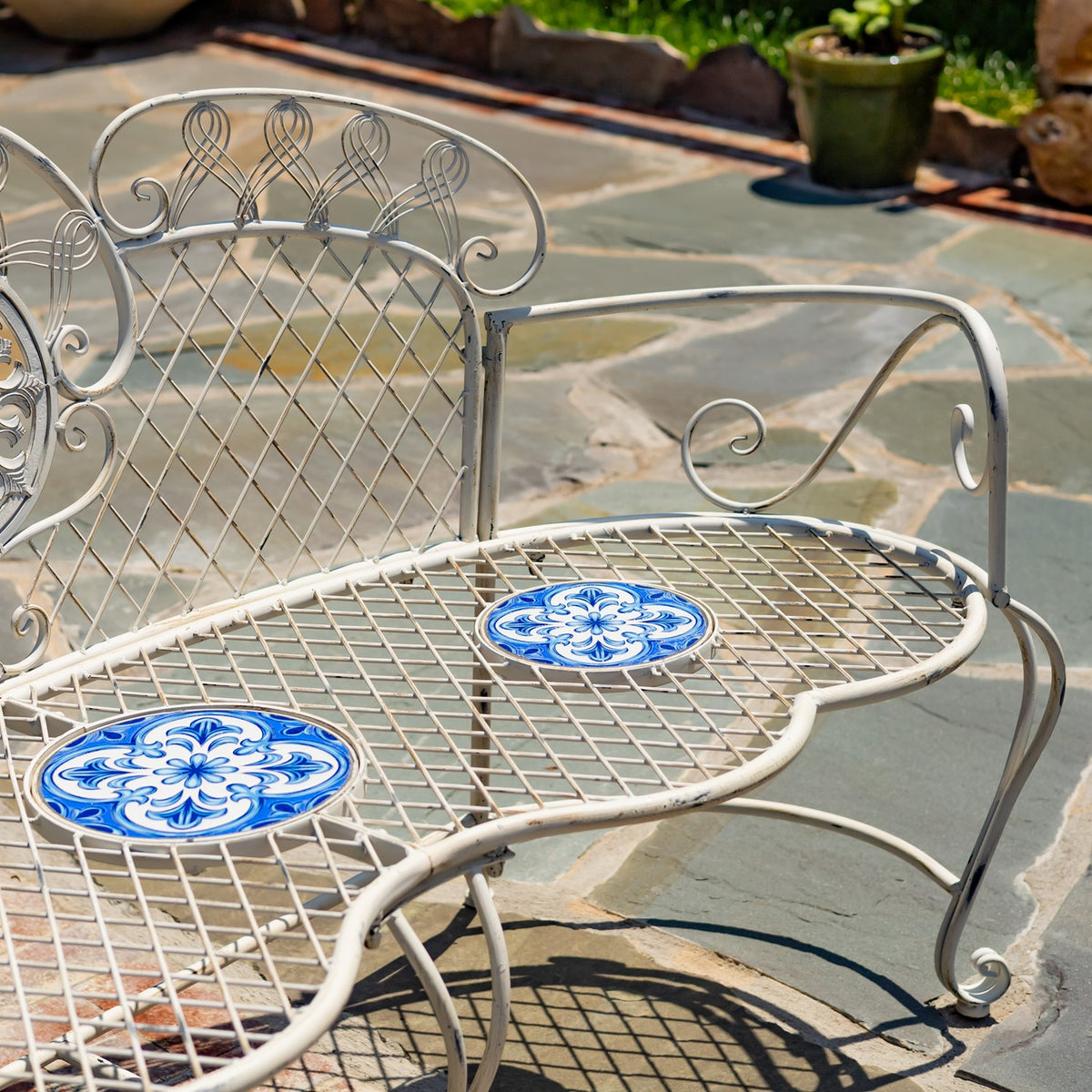 Close view of the curved arm, lattice seat, and patterned mosaic insets on the bench.