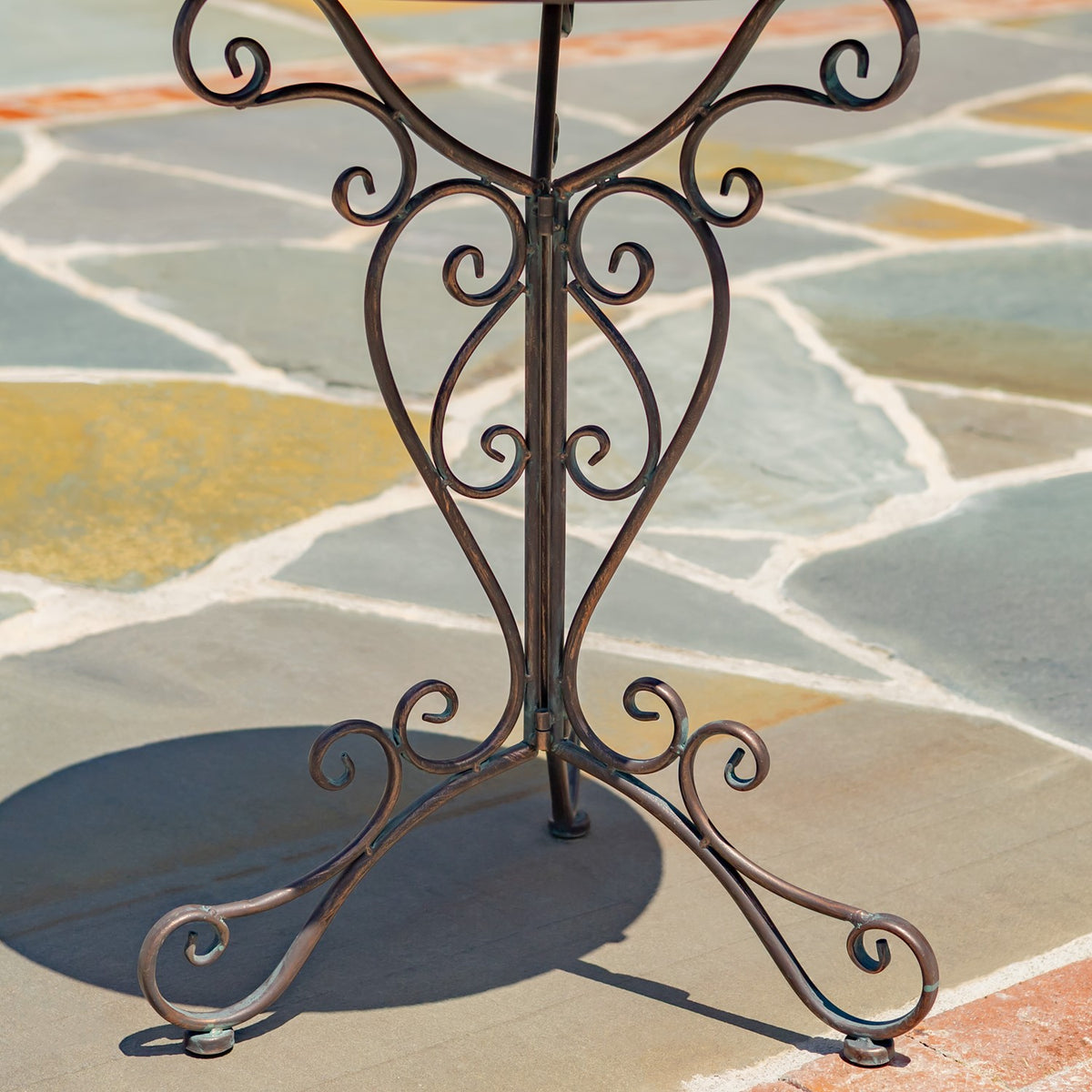 Close view of the dark metal stand's curled supports, central post, and curved feet.