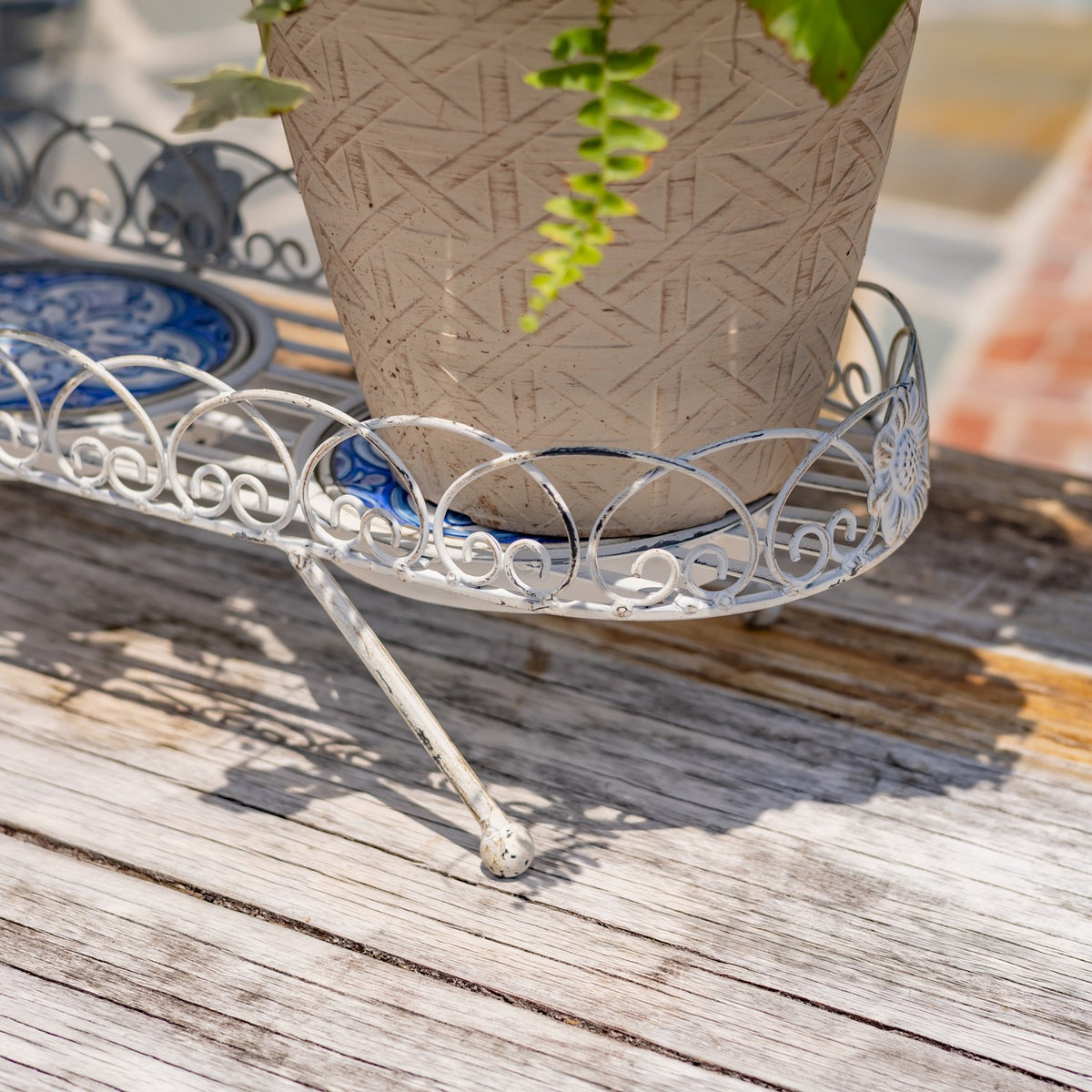 Close-up of the stand’s curved metal side, pot, and angled support leg.