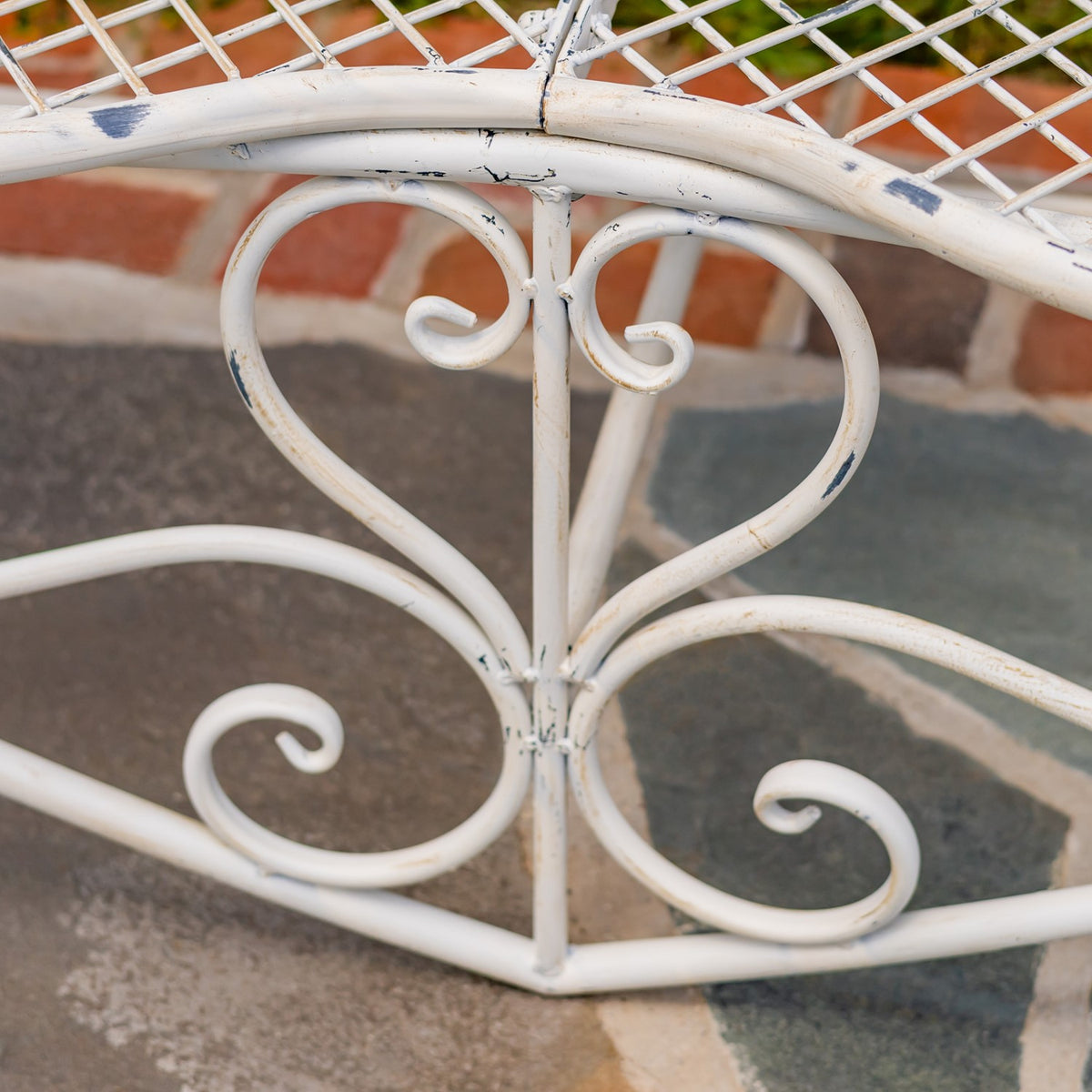 Close-up of curled metal scrollwork beneath the seat, with small areas of distressed finish visible.