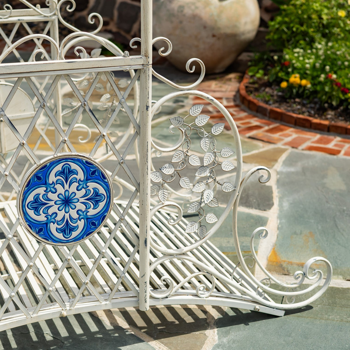 Close-up of a blue floral mosaic beside leaf-shaped metalwork and curled rails on the bridge.