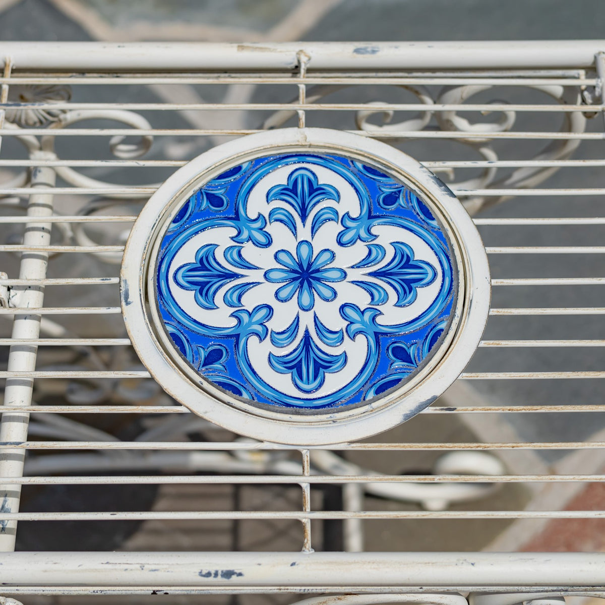 Overhead detail of a blue floral-patterned circular tile set among white metal slats.