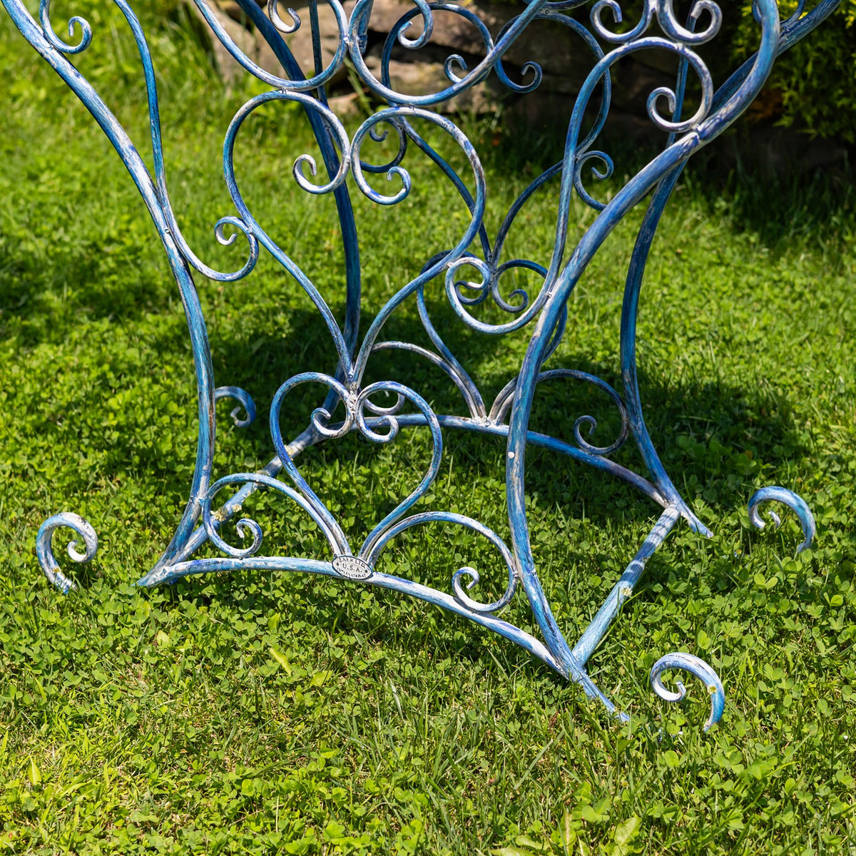 Close-up of the table’s curved blue iron supports and decorative scrollwork near the feet.