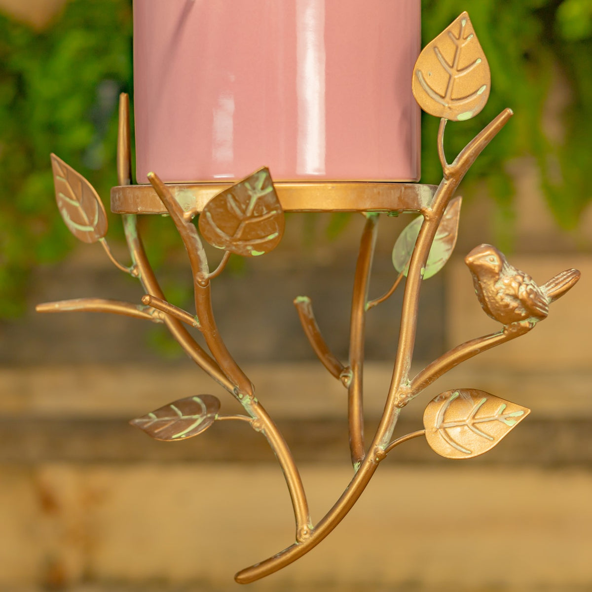 Close-up of the birdhouse’s curved branch-shaped metal hanger, decorative leaves and perched bird.