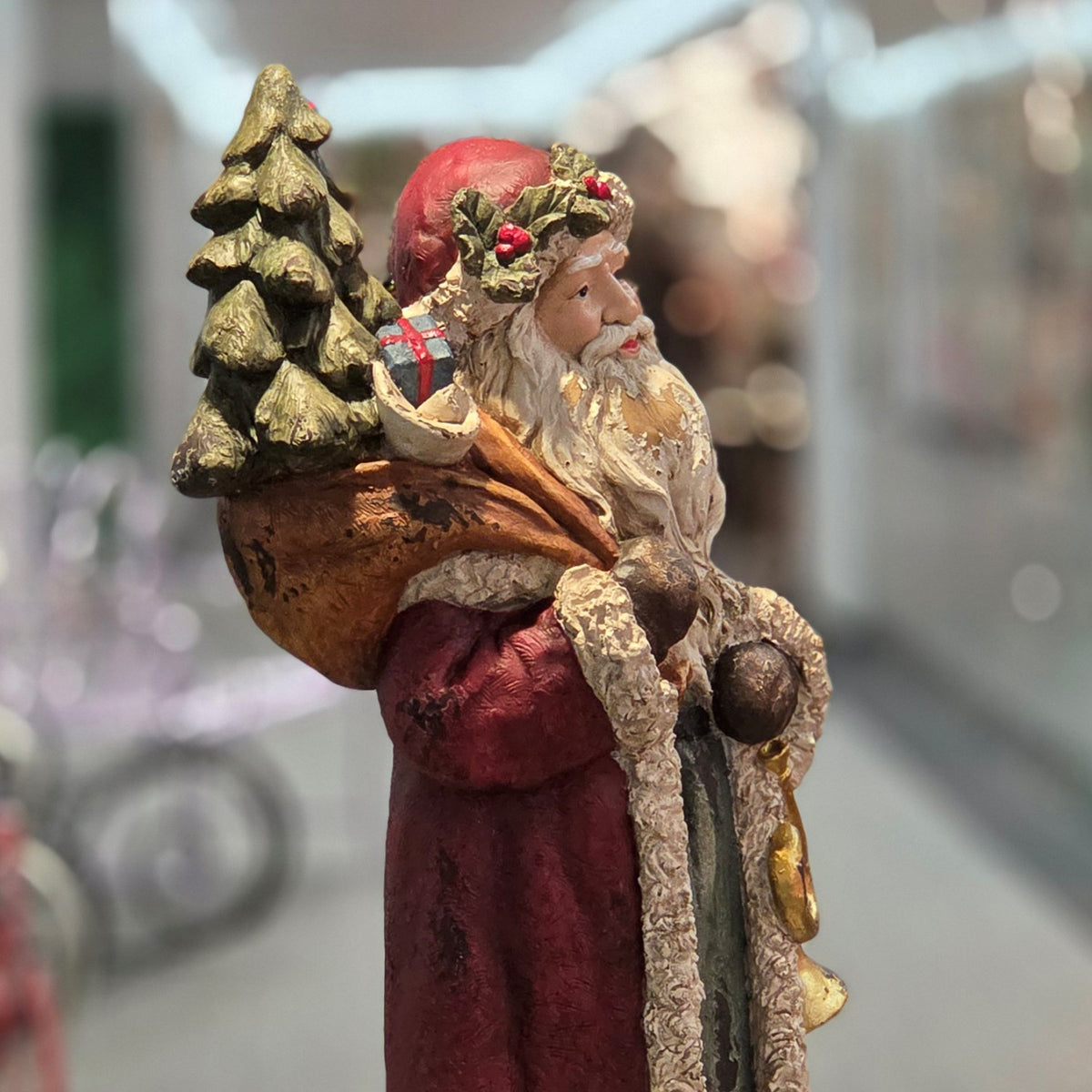 Side view of Santa carrying a decorated Christmas tree