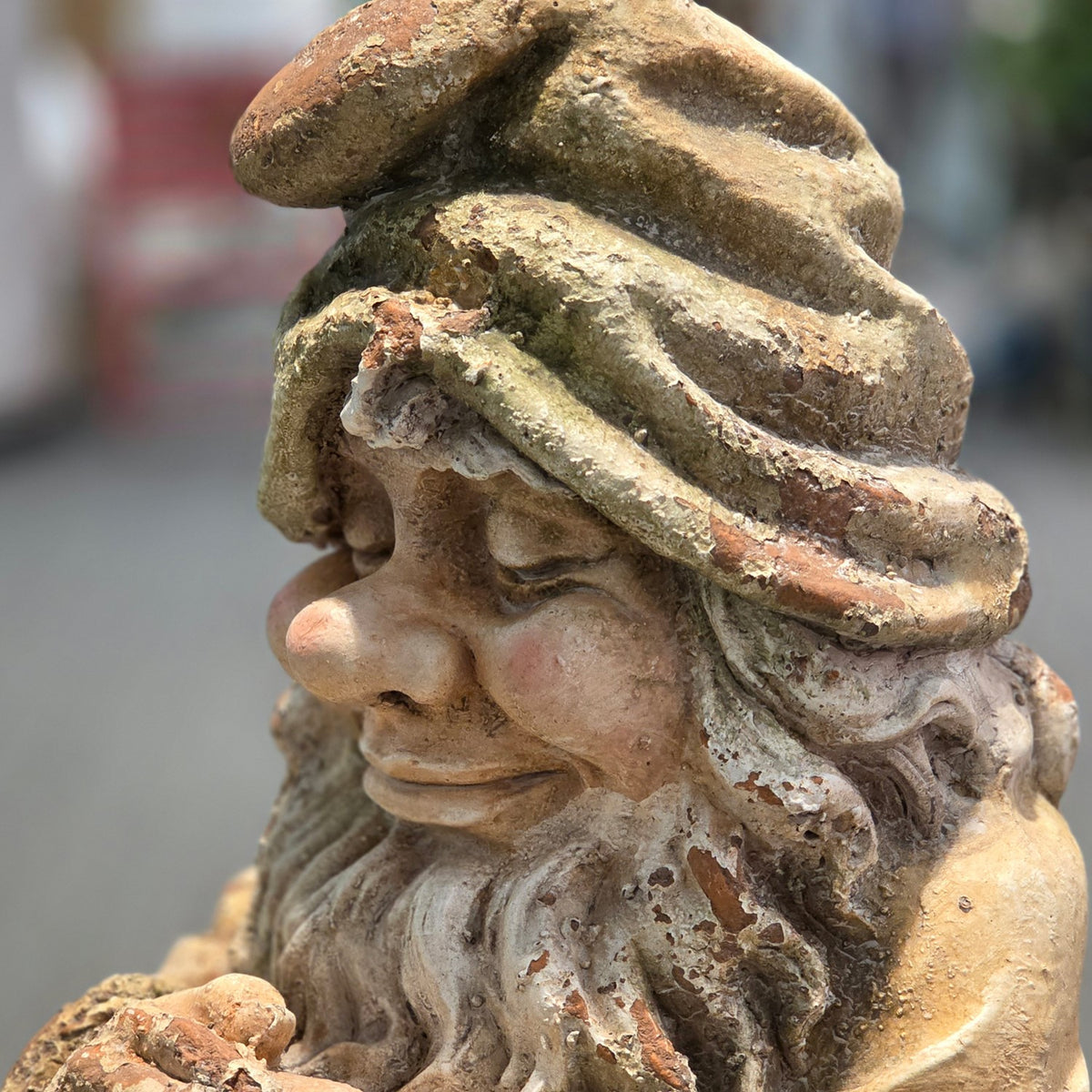 Close side view of the gnome's sculpted face, hat, and beard