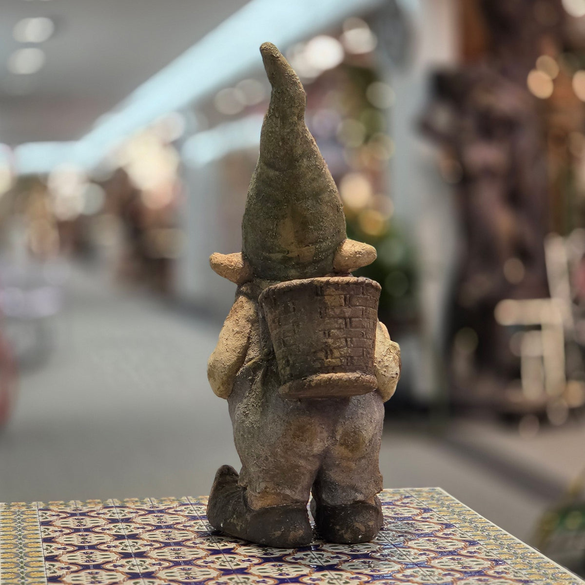 Rear view of the distressed gnome showing its back basket planter and textured finish