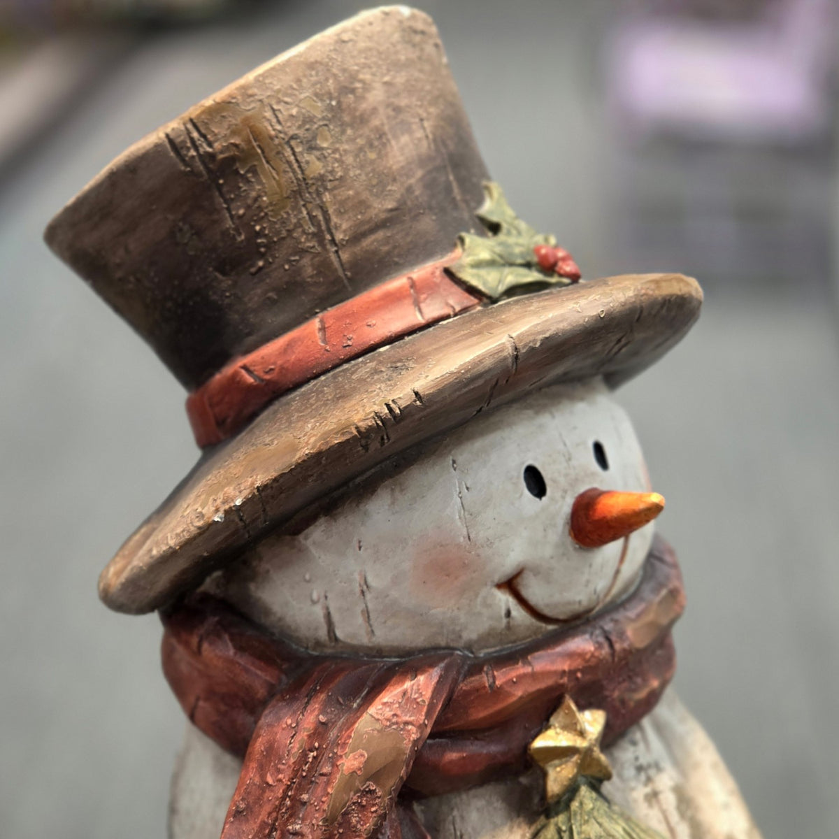 Angled close-up of the snowman's top hat, face, and red scarf
