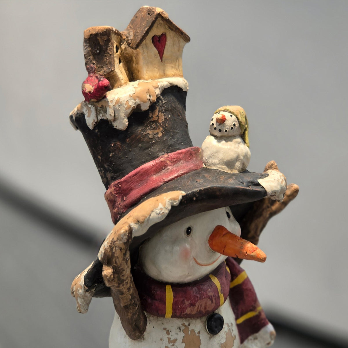 Close-up of the snowman's tall hat, small bird detail, and upper face