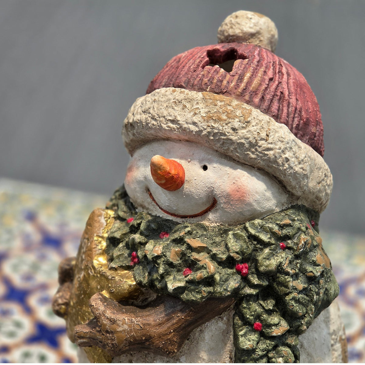 Close-up of snowman face and knit-look red hat with a candle opening