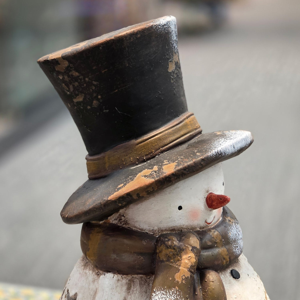 Close view of the snowman's distressed black top hat and scarf
