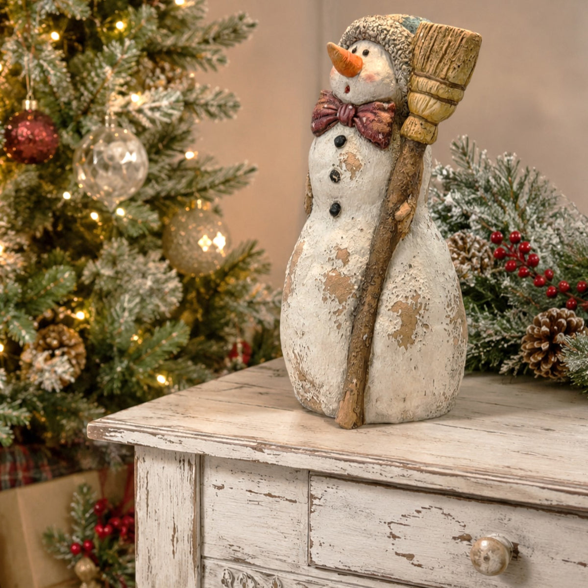 Angled view of the snowman figurine and broom on a distressed white table