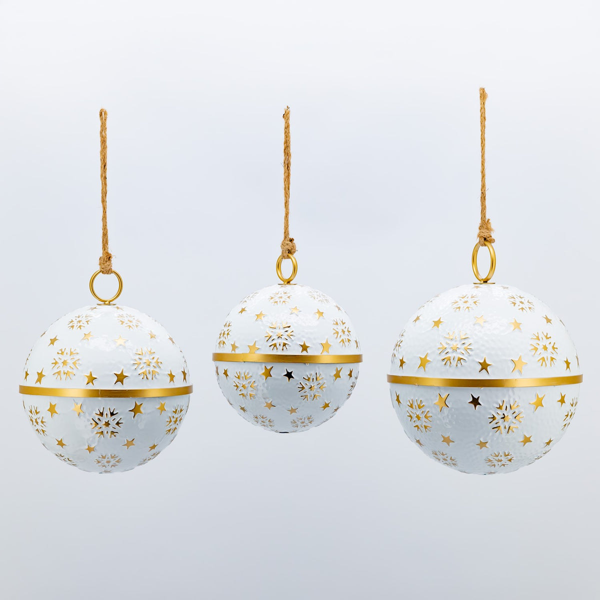 Three white spherical ornaments with gold snowflake and star decorations arranged against a plain background.