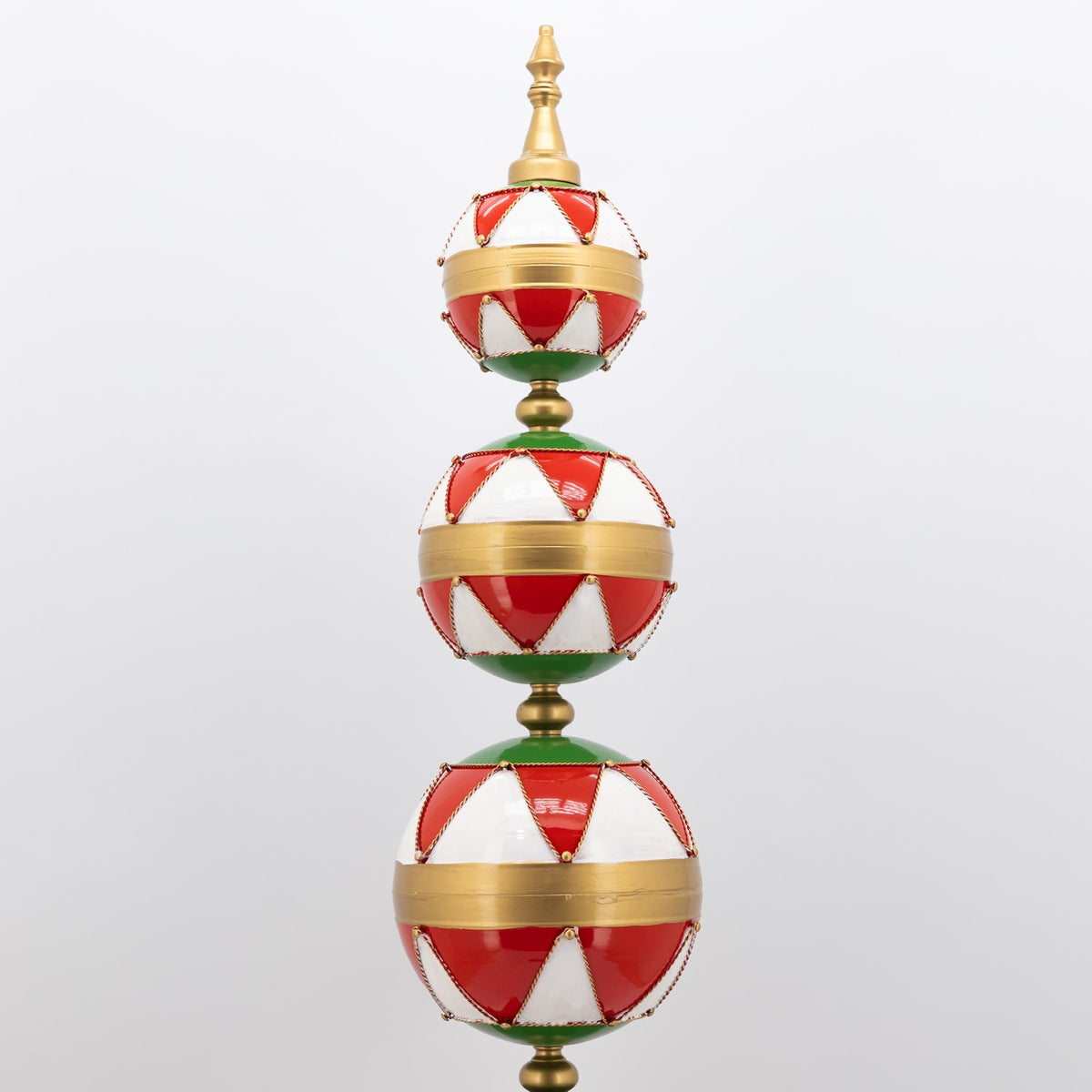 Upper section of the display tower, showing three striped ornaments and its pointed gold finial.